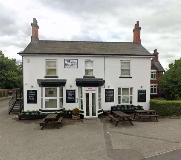 A 2 story white pub with dark brown wooden benches outside.