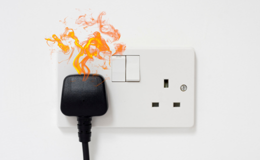 A double UK plug socket with flames coming out of the plug.