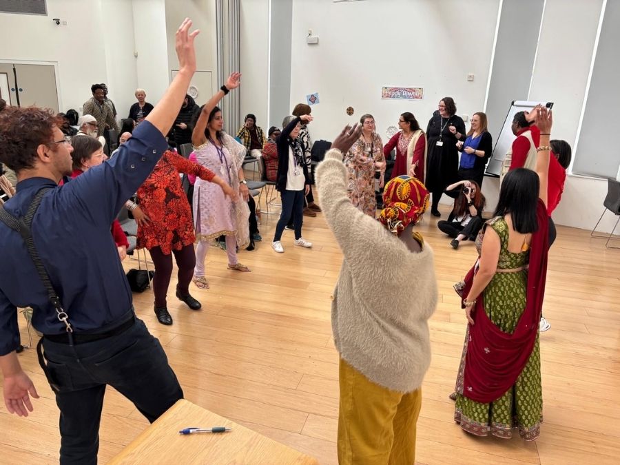 A room full of people dancing in a circle. They're celebrating Diwali.