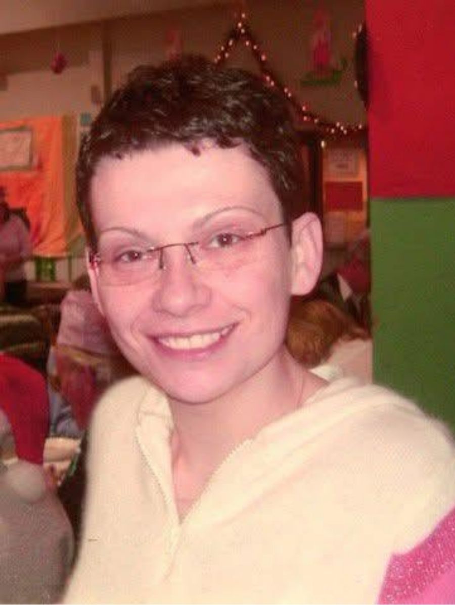 Young Lisa with short hair and glasses is smiling widely.