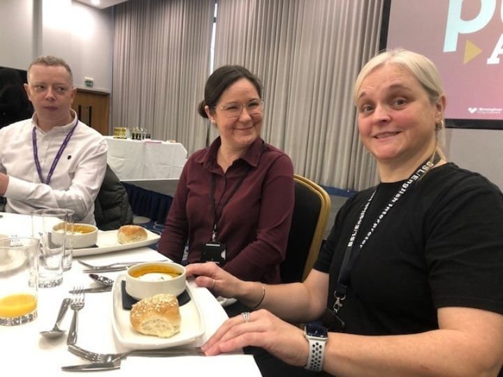 Two female interpreters seated at a table with soup and bread rolls in front of them.