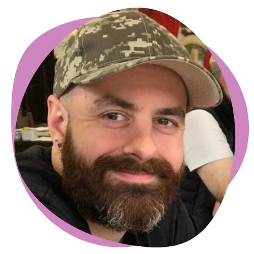 A white man wearing a cap with a brown and grey beard.