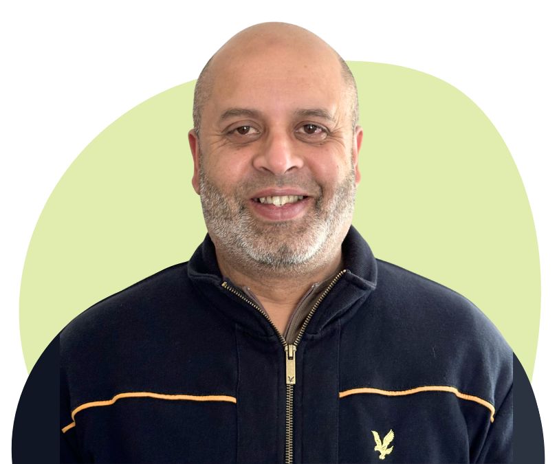 Asian man with grey stubble against a green background.