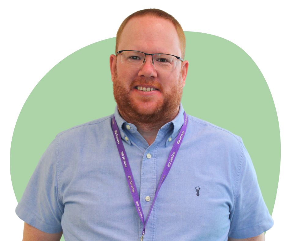 White man with short red hair and beard against a green background.
