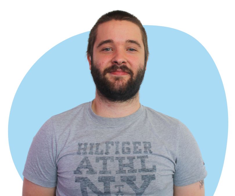 White man with short brown hair and a beard against a blue background.