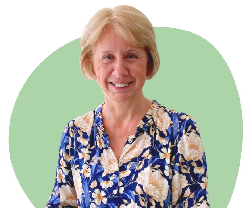 White woman with short light blonde hair against a green background.