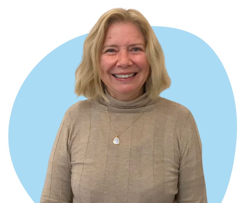 White woman with short blonde hair against a blue background.