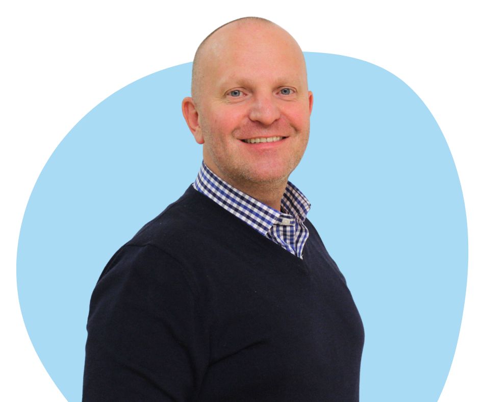 White bald man with stubble against a blue background.
