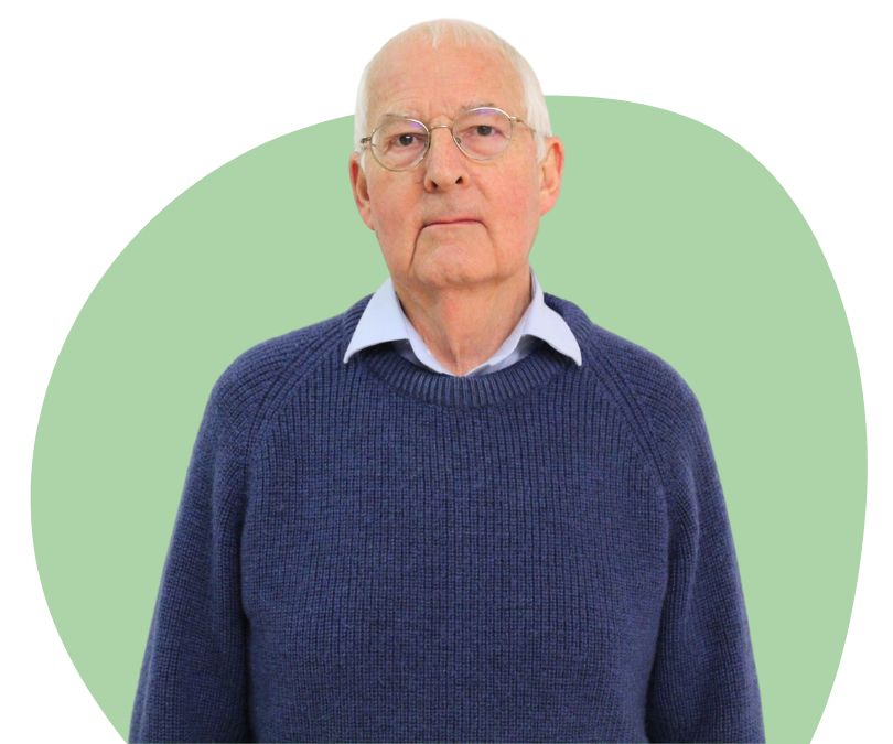 White man with white hair and glasses against a green background.