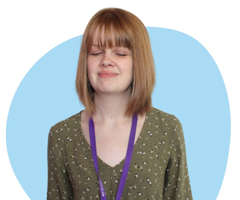 White woman with shoulder length dark blonde hair against a blue background.