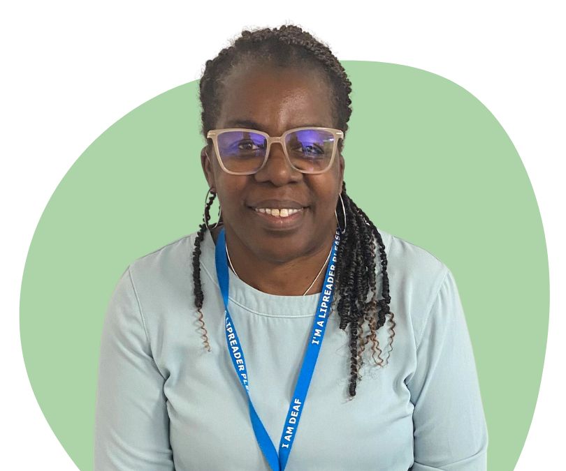 Black woman black hair in braids and glasses against a green background.