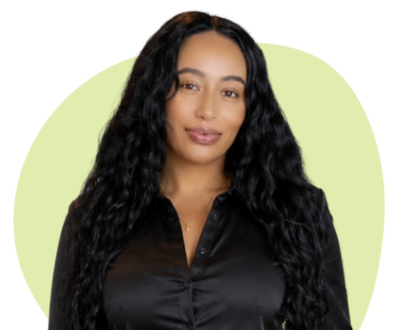 A black woman with long, curly black hair against a light green background.