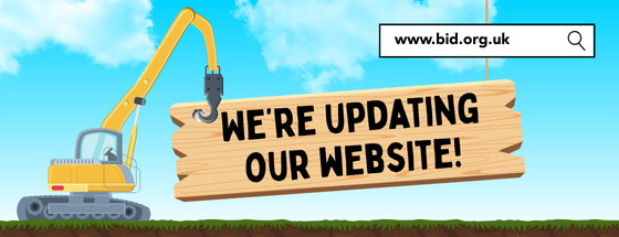 A cartoon graphic with a yellow crane hoisting up a wooden plank with bold, black words that read 'we're updating our website'.