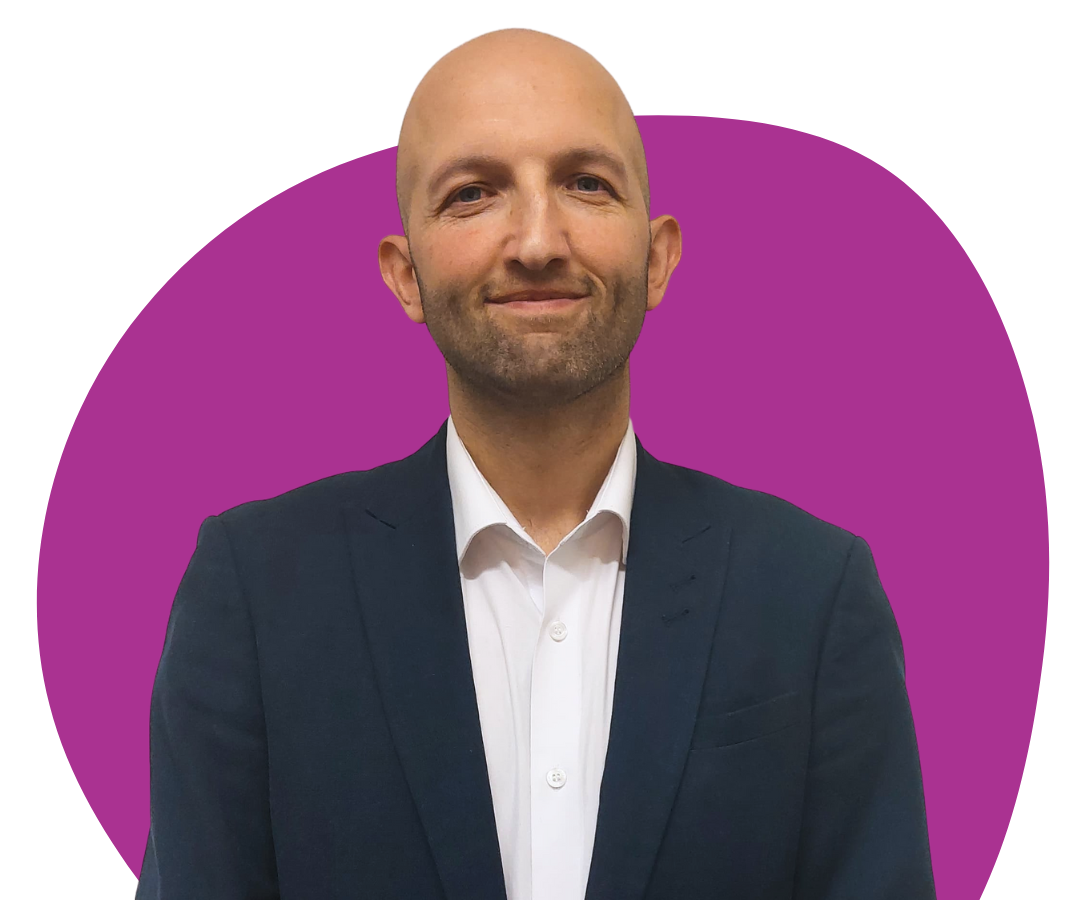A white, bald man with stubble against a purple background.