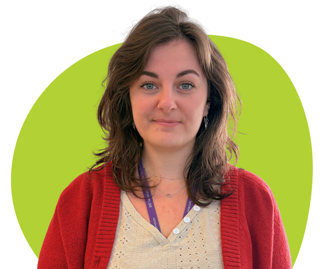 A white woman with shoulder length, wavy brown hair against a light green background.