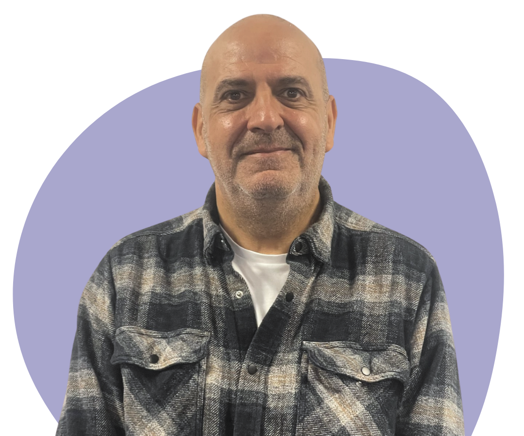 Greek, bald man with stubble against a blue background.